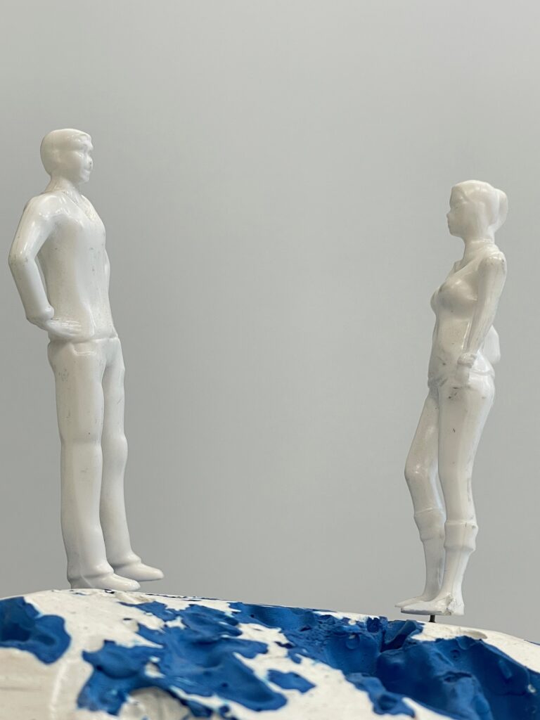 Tapio Haapalan sekatekniikka veistos, jossa mies- ja naisoletettu kohtaavat rannalla